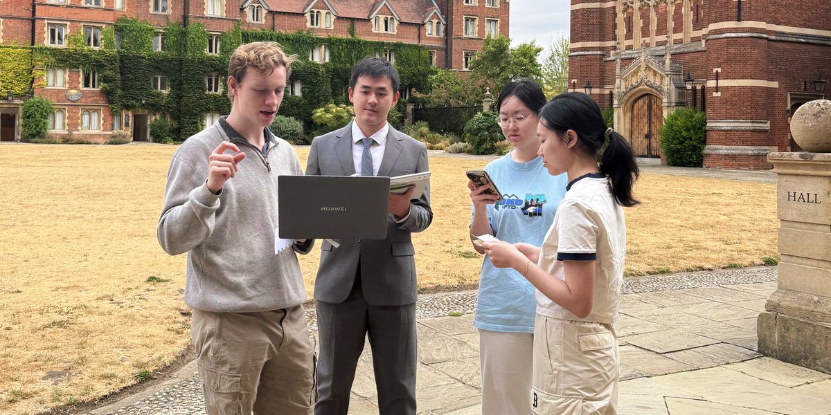 Three students and a teacher look at a laptop in a court at Selwyn College