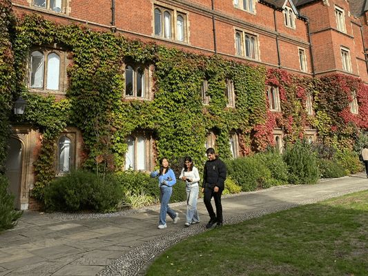 Students walking past an ivy-covered building at Selwyn College