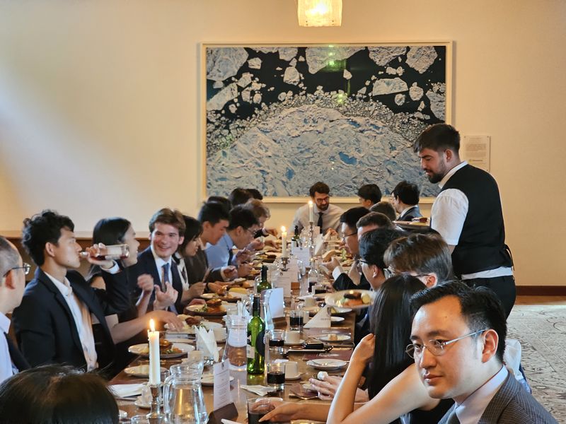 Students along a candle-lit table at a formal dinner in 2026