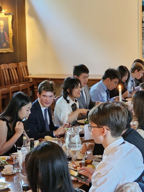 Students at a long table during a candle-lit formal dinner in summer 2026