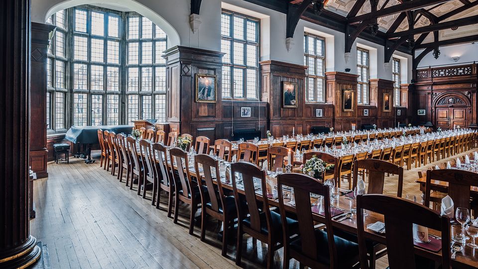 The Selwyn dining hall, with tall windows and a dark wooden roof