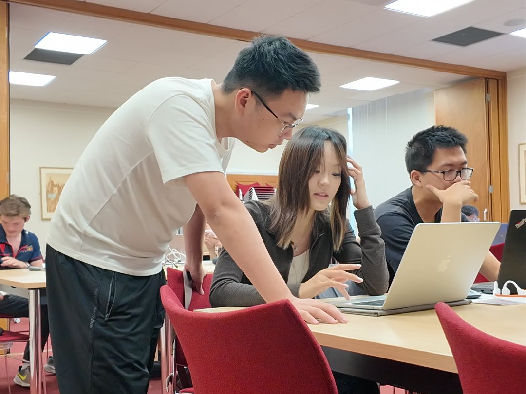 A teacher helps a team at their laptop