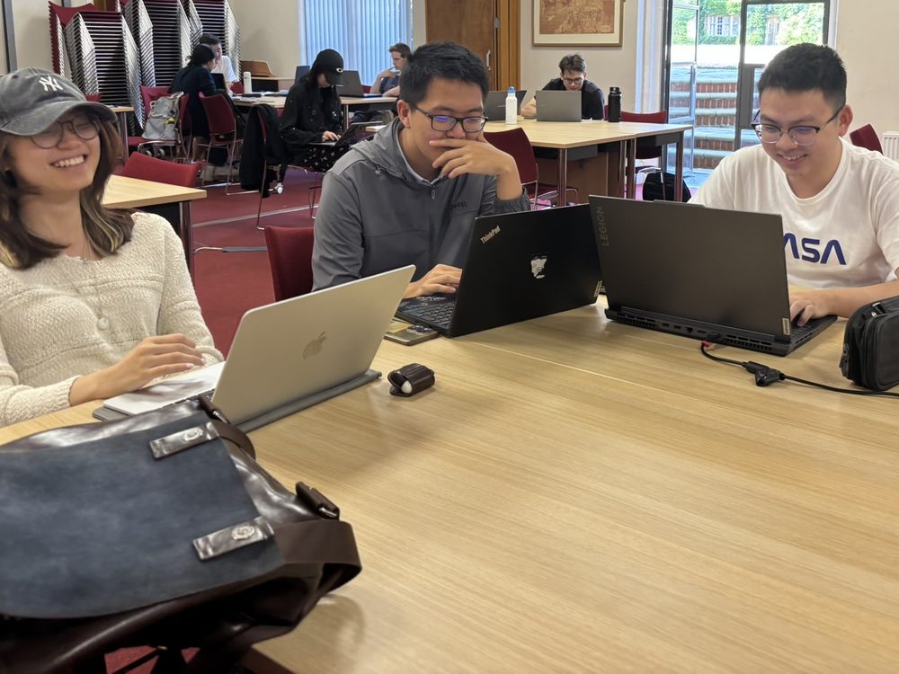 Three students smiling as they work at their laptops