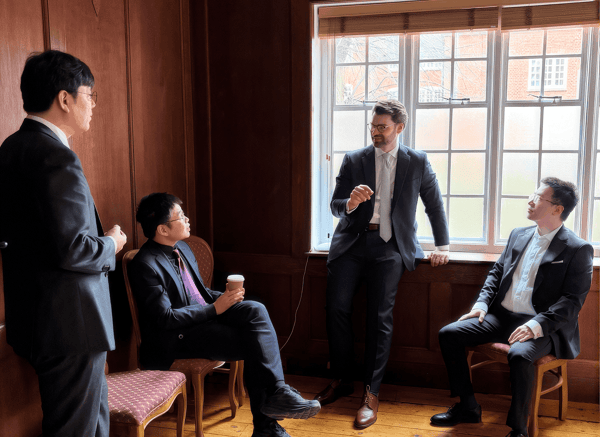 Cambridge teachers talking in a wood-panelled college room