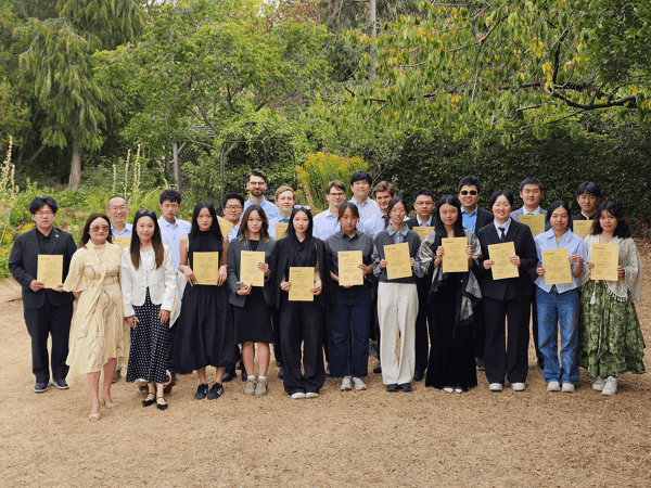Students holding their certificates in a college garden